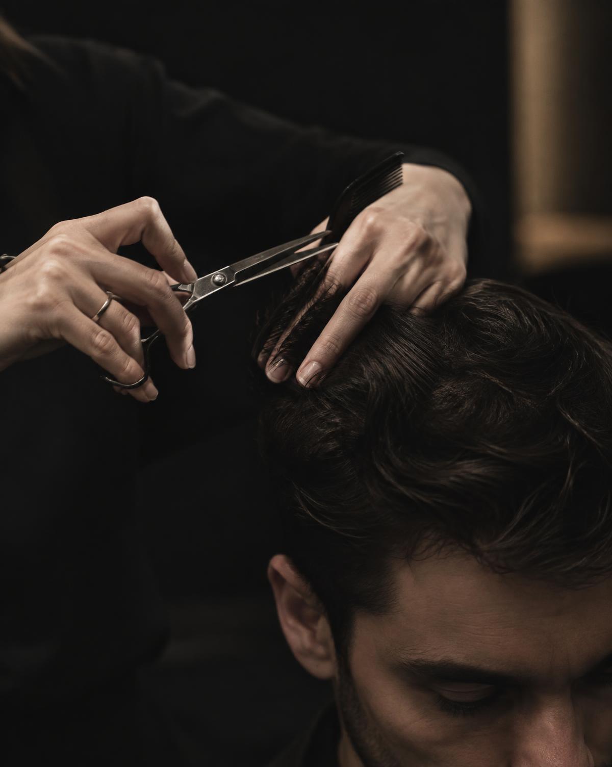 Stylist scissor-cutting a man's hair over a comb