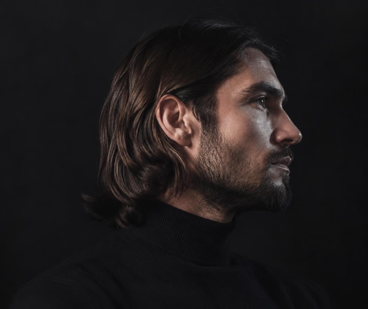 Profile of a man with shoulder-length hair and beard