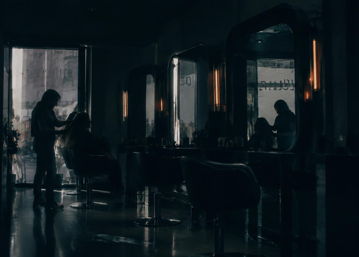Silhouetted stylist at work, reflected in salon mirrors